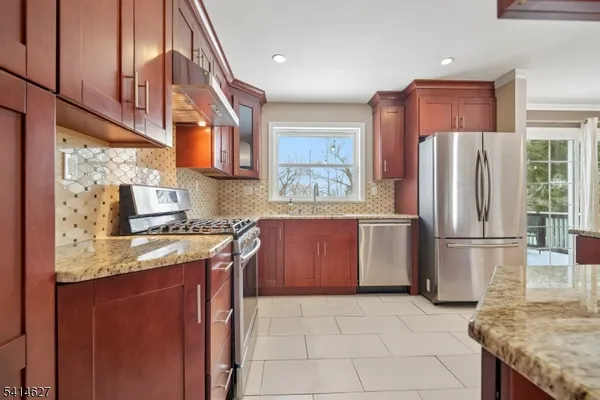 a kitchen with granite countertop a refrigerator and a stove top oven