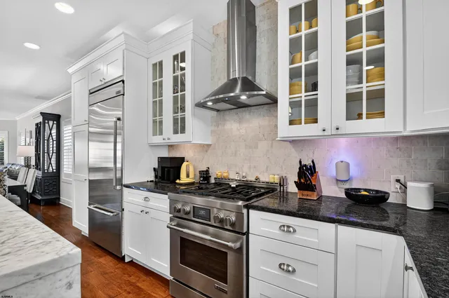 a kitchen with stainless steel appliances granite countertop a stove and a white cabinets