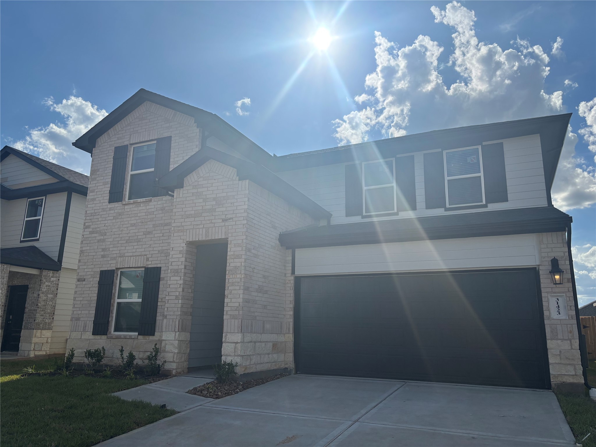 31423 Harp Ridge Drive Fulshear, TX 77441 - Photo 1 of 45 Modern two-story home with a brick facade and attached two-car garage, set against a clear blue sky.