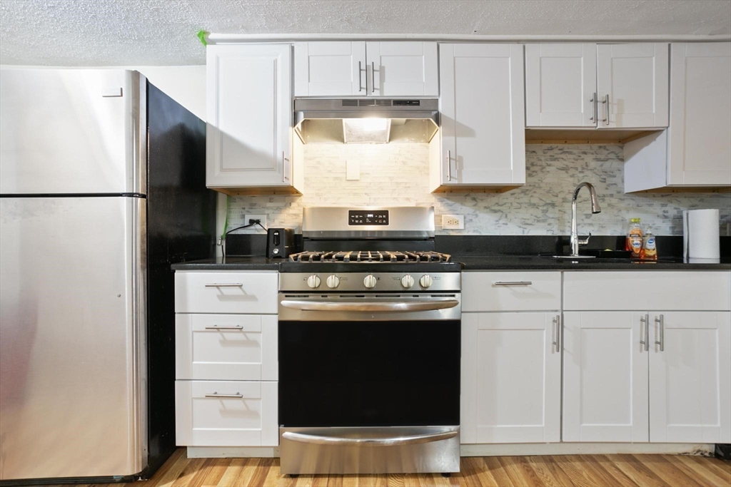 55 A Lanark Road, Unit A Boston, MA 02135 - Photo 8 of 18 a kitchen with stainless steel appliances granite countertop a stove a refrigerator and a granite counter tops