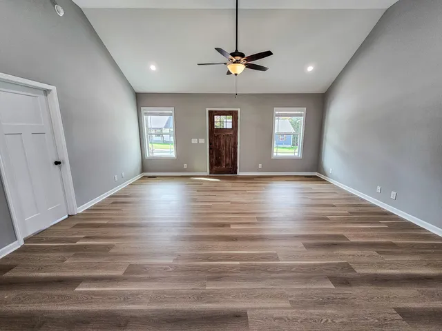 a view of an empty room with window and wooden floor