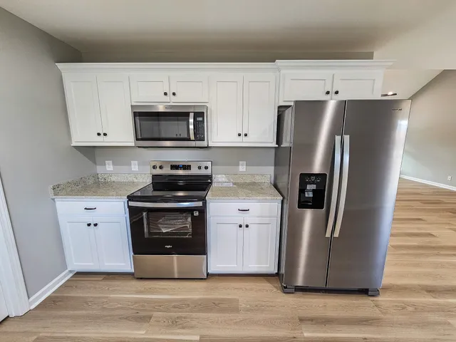 a kitchen with stainless steel appliances a refrigerator stove and white cabinets