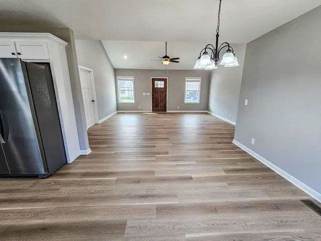a view of a livingroom with a chandelier wooden floor and a ceiling fan