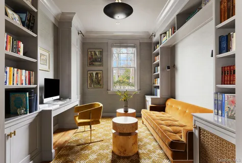 a living room with furniture a bookshelf and a window