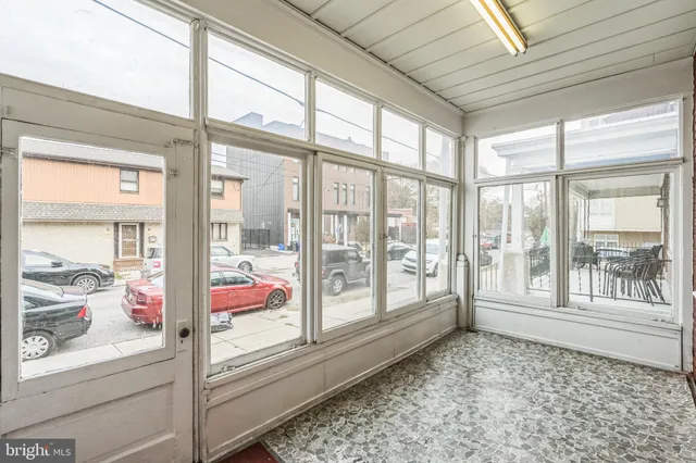 an empty room with chandelier fan and windows