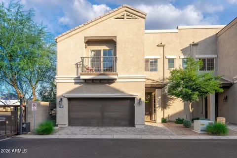 a front view of a house with garage and plants