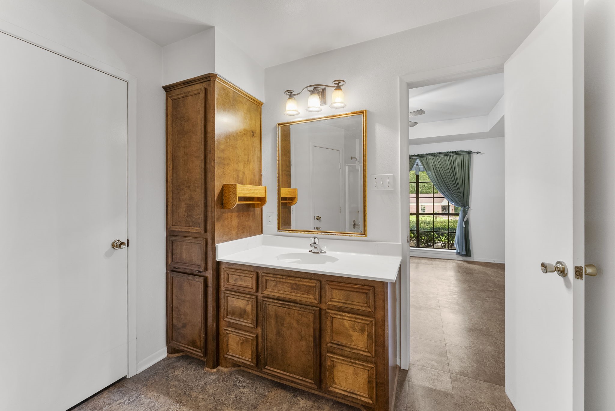 202 Sunset Boulevard Conroe, TX 77303 - Photo 33 of 50 This inviting primary bathroom features warm wooden cabinetry, a sleek integrated sink, and elegant lighting, seamlessly connecting to a bright room with a charming view.