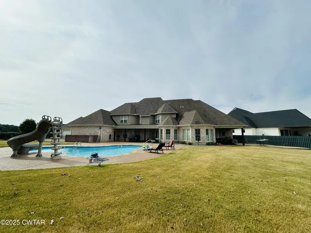 a view of a house with swimming pool and a yard