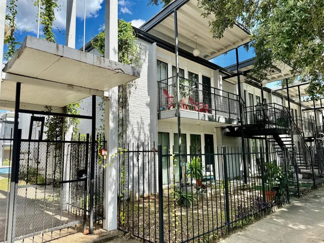 a view of a brick house with large windows and a small yard