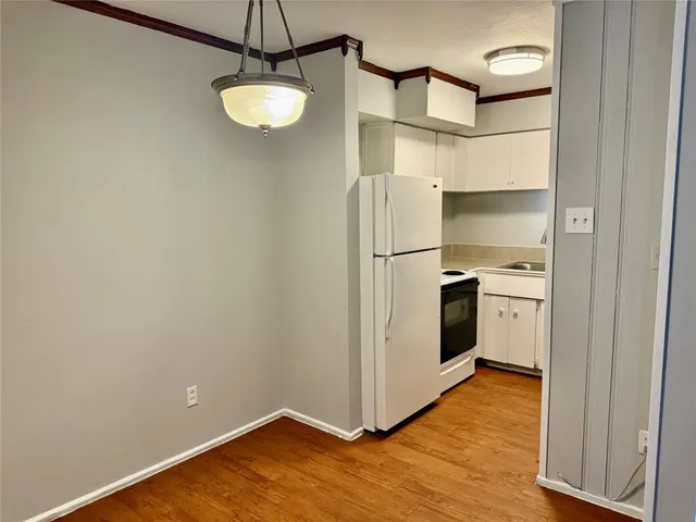 a view of a big room with wooden floor and a kitchen