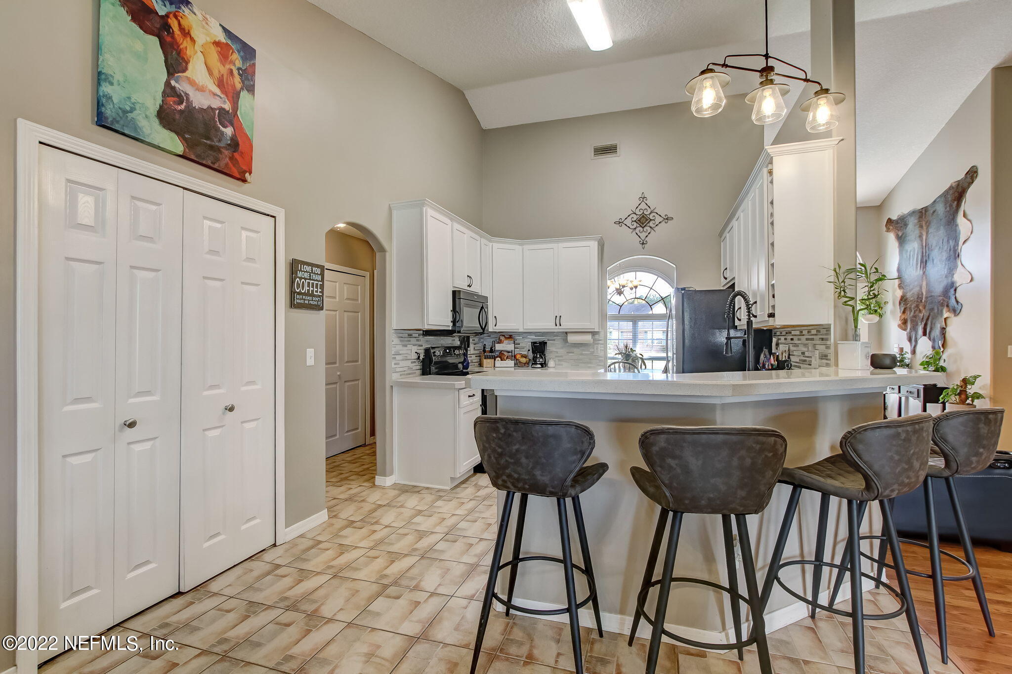 54025 Paddock Court Callahan, FL 32011 - Photo 13 of 47 a kitchen with stainless steel appliances a dining table chairs refrigerator and cabinets