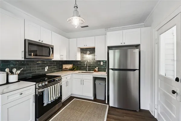 a kitchen with a refrigerator a microwave a sink and cabinets