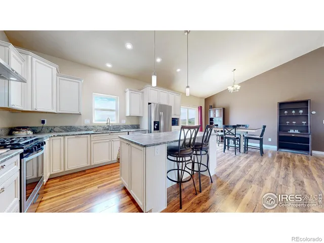 a kitchen with stainless steel appliances kitchen island granite countertop a table chairs sink and cabinets