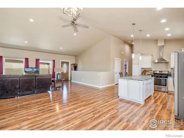 a open kitchen with stainless steel appliances granite countertop a refrigerator a sink a stove and oven with wooden floor