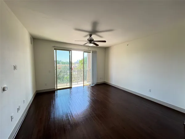 a view of a room with wooden floor and a ceiling fan