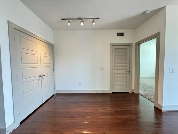 a view of an empty room with wooden floor and closet