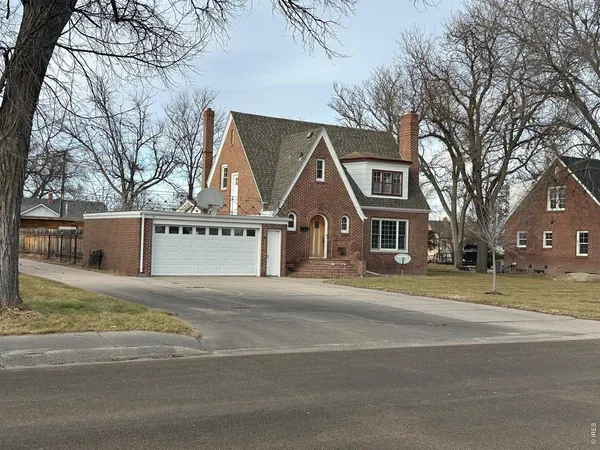 a view of a house next to a road with large trees