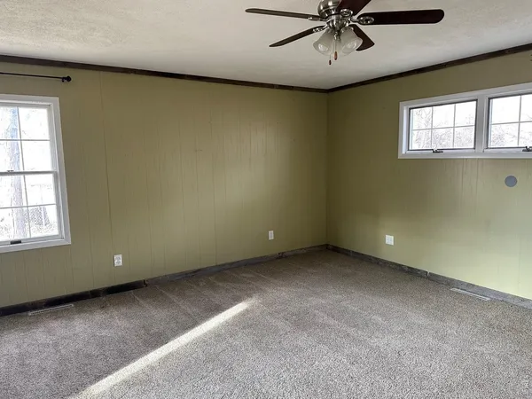 an empty room with a ceiling fan and a window