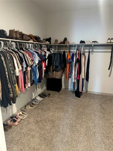 a view of walk in closet with clothes and shoes