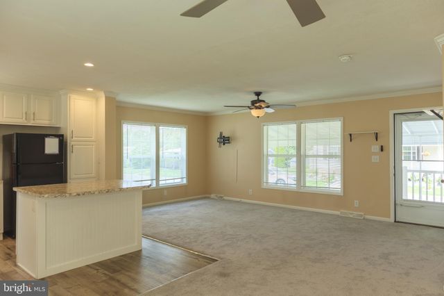 a view of an empty room with a window and a kitchen