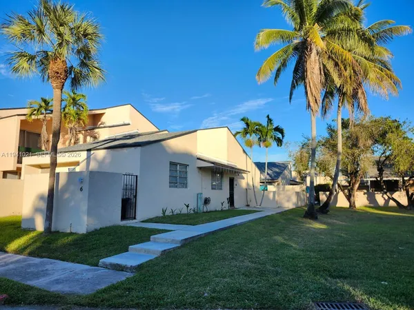 a view of a white house with a big yard and palm trees