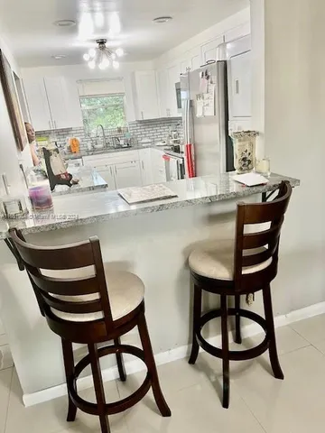a kitchen with stainless steel appliances kitchen island a table chairs sink and cabinets