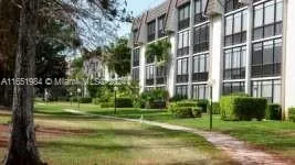 a view of a tall building with a big yard and plants