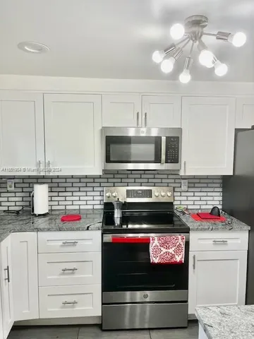 a kitchen with granite countertop a stove and a microwave