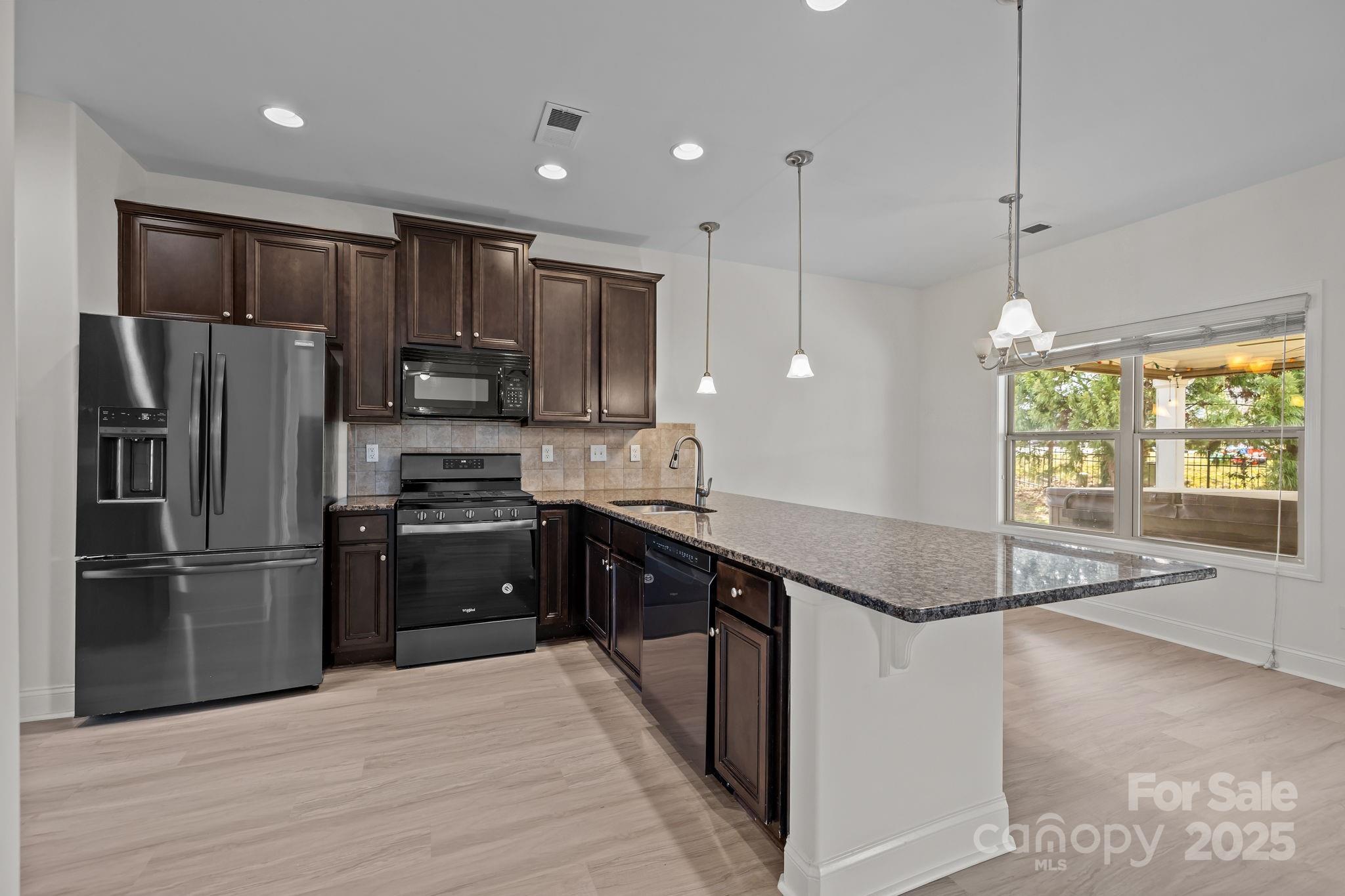 7020 Sedgewick Road Indian Trail, NC 28079 - Photo 8 of 42 a kitchen with stainless steel appliances granite countertop a refrigerator a sink a stove a microwave and wooden cabinets