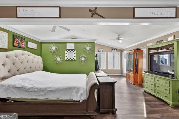 a bedroom with a large bed and a flat tv screen on dresser