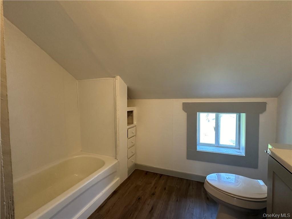 1399 State Rte 55, Unit 11 Clintondale, NY 12515 - Photo 16 of 21 Full bathroom with vaulted ceiling, vanity, toilet, shower / bathing tub combination, and hardwood / wood-style floors