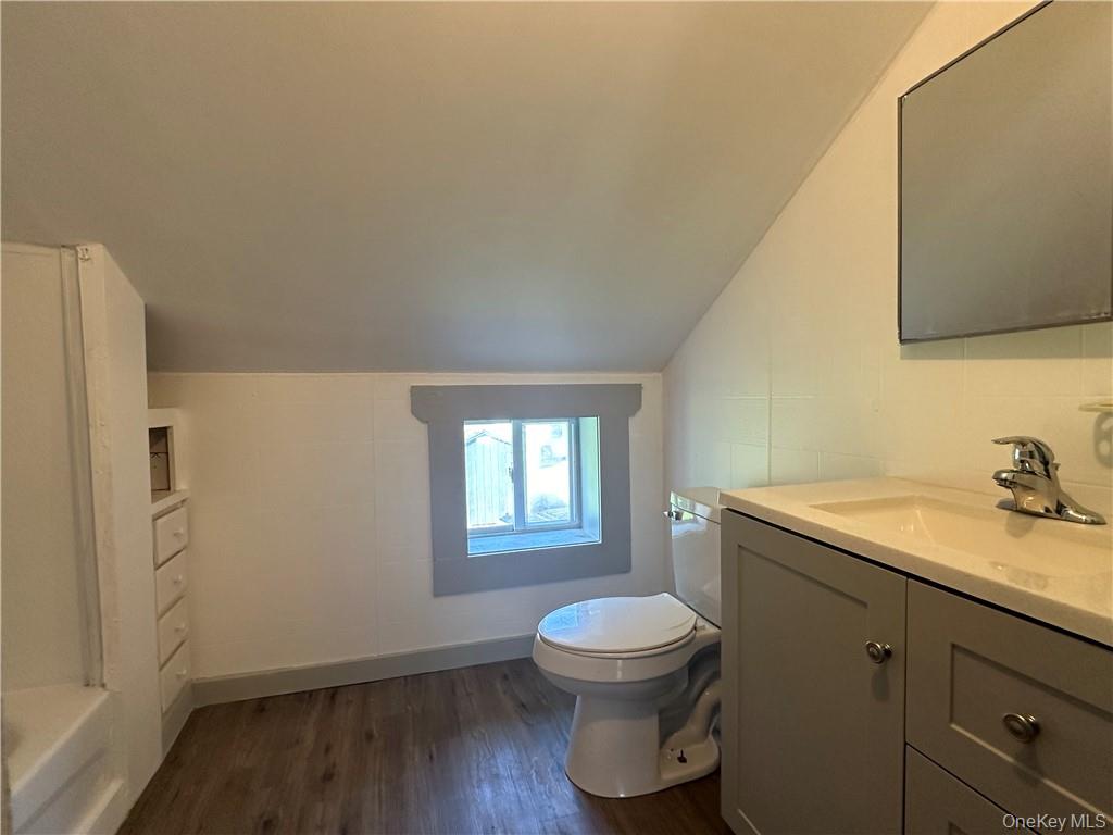 1399 State Rte 55, Unit 11 Clintondale, NY 12515 - Photo 17 of 21 Bathroom featuring a bath, hardwood / wood-style flooring, vaulted ceiling, vanity, and toilet