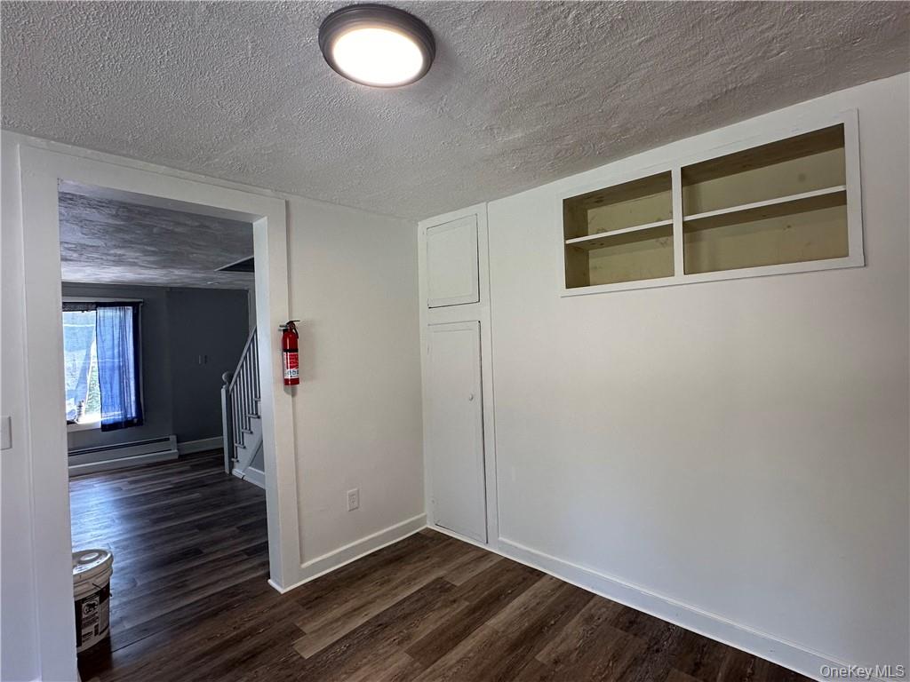 1399 State Rte 55, Unit 11 Clintondale, NY 12515 - Photo 7 of 21 Unfurnished room featuring a textured ceiling, dark wood-type flooring, and a baseboard radiator