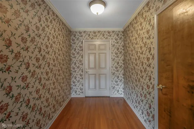 a view of a hallway with wooden floor and a bathroom