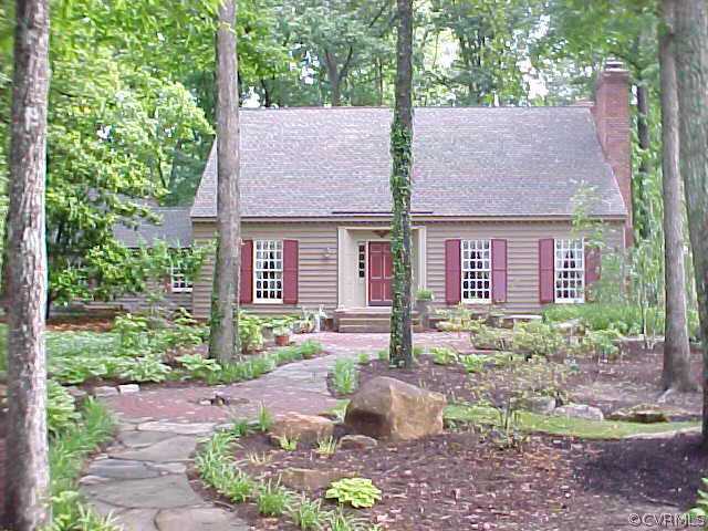 a view of a brick house with a yard plants and large tree