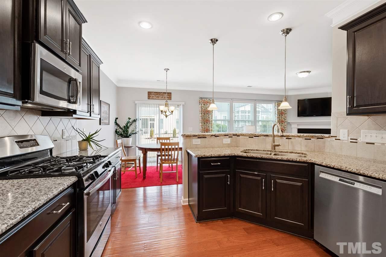 1013 Traditions Meadow Drive Wake Forest, NC 27587 - Photo 8 of 30 a kitchen with stainless steel appliances granite countertop a stove top oven a sink dishwasher and wooden cabinets with wooden floor
