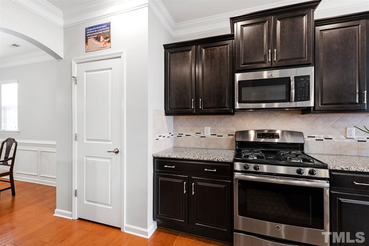 1013 Traditions Meadow Drive Wake Forest, NC 27587 - Photo 9 of 30 a kitchen with granite countertop wooden cabinets and stainless steel appliances