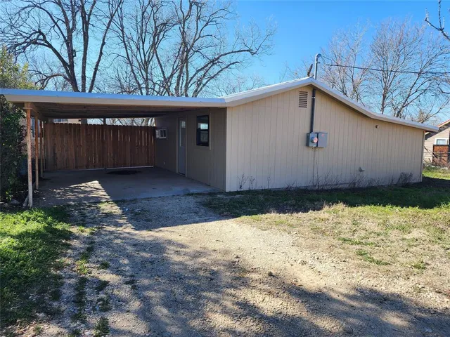 a backyard of a house with a large tree and wooden fence