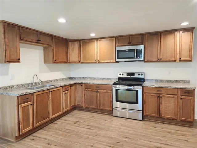 a kitchen with granite countertop wooden cabinets stainless steel appliances and a sink