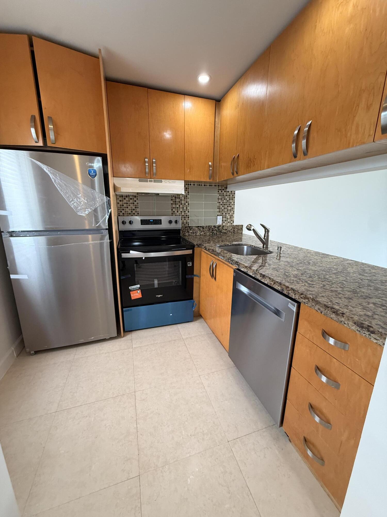 875 Northwest 13th Street, Unit 405 Boca Raton, FL 33486 - Photo 6 of 16 a kitchen with stainless steel appliances granite countertop a sink and a refrigerator