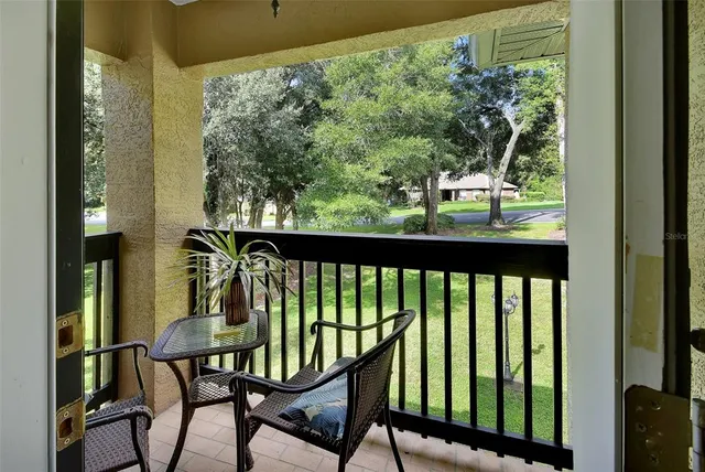 a living room with couch floor to ceiling windows and a ceiling fan