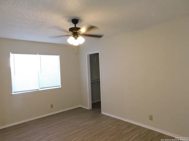 a view of an empty room with a window and wooden floor