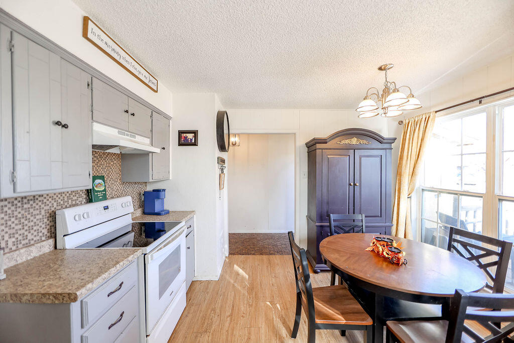 6001 14th Street Lubbock, TX 79416 - Photo 11 of 31 a kitchen with stainless steel appliances granite countertop a stove a sink dishwasher a dining table and chairs with wooden floor