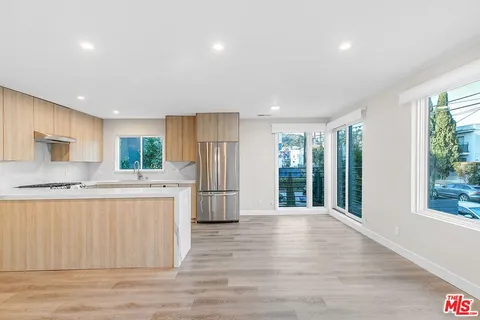 a kitchen with stainless steel appliances granite countertop a refrigerator a sink dishwasher a stove and a refrigerator with wooden floor