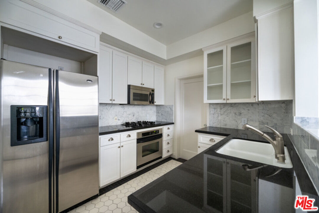 9237 Doheny Road West Hollywood, CA 90069 - Photo 7 of 14 a kitchen with stainless steel appliances granite countertop a stove a refrigerator and a sink