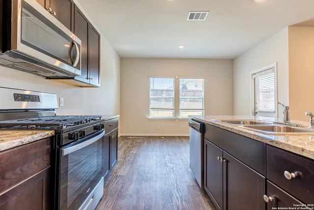 a kitchen with a stove a sink and wooden floor