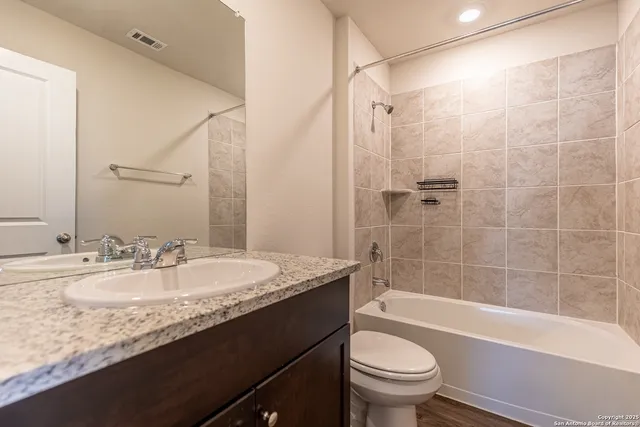 a bathroom with a granite countertop sink a toilet a mirror a bathtub and shower