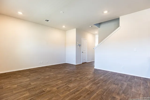 an empty room with wooden floor and white walls