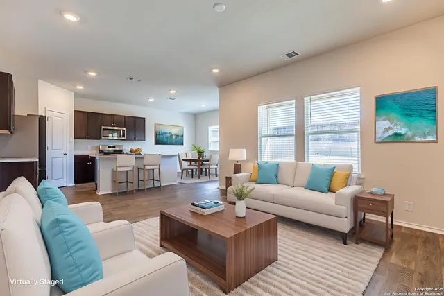 a living room with furniture wooden floor kitchen view and a flat screen tv