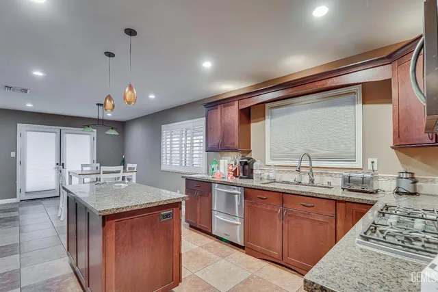 a kitchen with kitchen island granite countertop a sink stove and cabinets